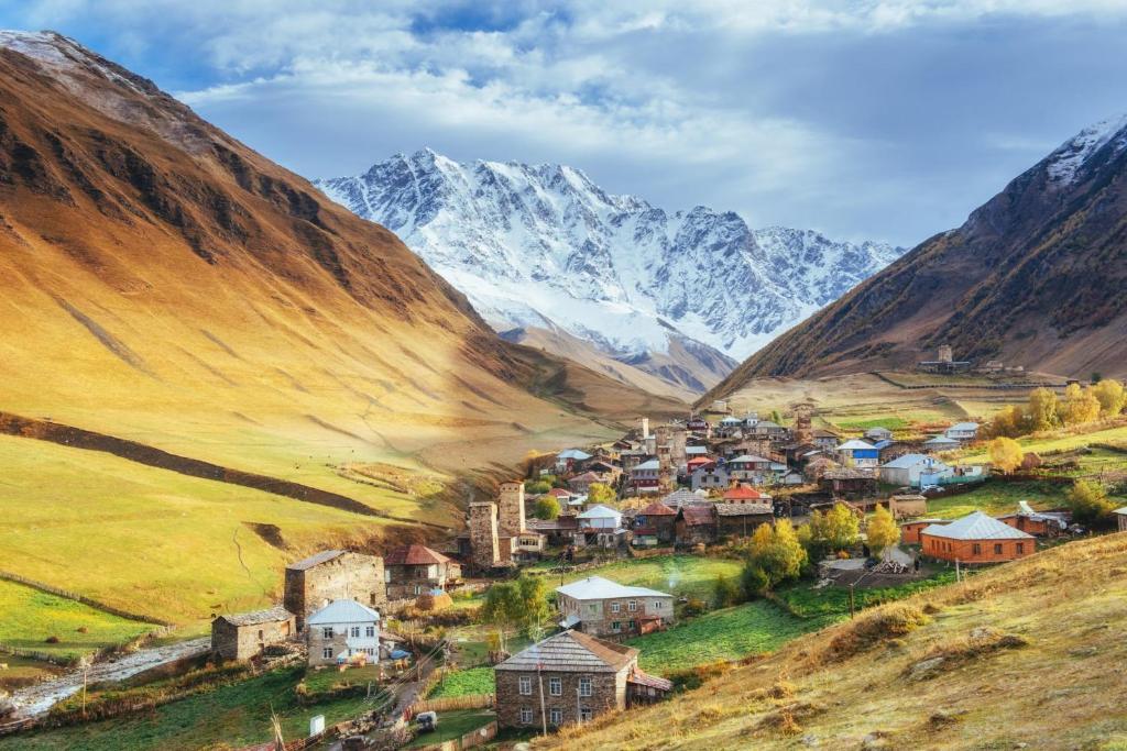 un pequeño pueblo en un valle con montañas en el fondo en Hotel-Cafe Koshki Ushguli, en Ushguli