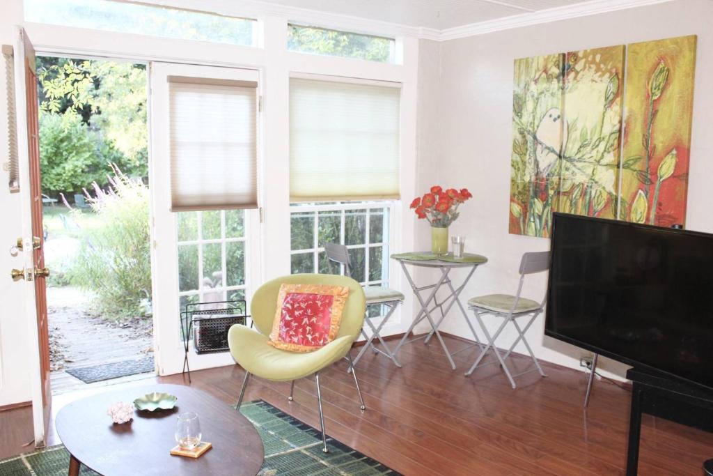 ein Wohnzimmer mit einem TV und einem gelben Stuhl in der Unterkunft Cottage at Mulberry in Atlanta