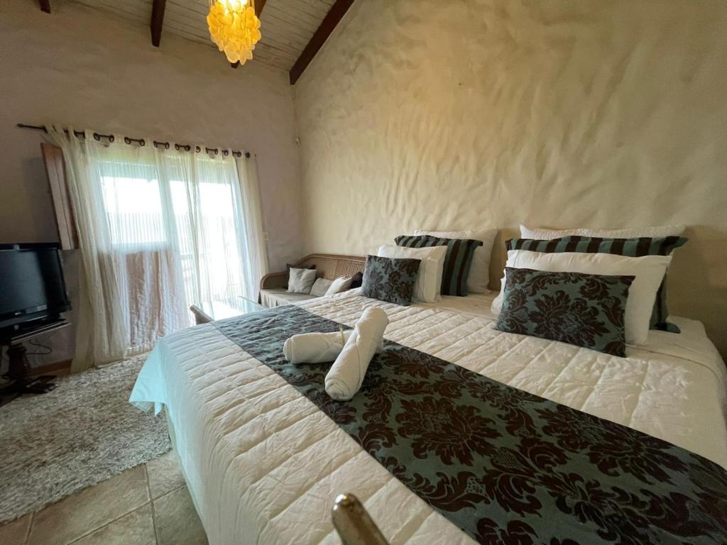 - une chambre avec un grand lit et une télévision dans l'établissement Suítes - Casa Jardim Chapada, à Alto Paraíso de Goiás
