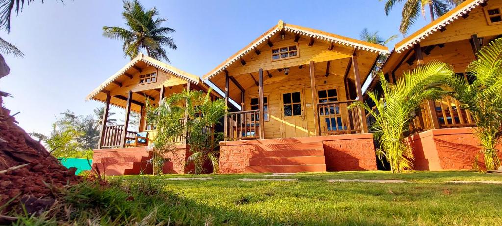 una gran casa de madera con palmeras delante en Parisa beach resort Tarkarli Bhogwe en Malvan