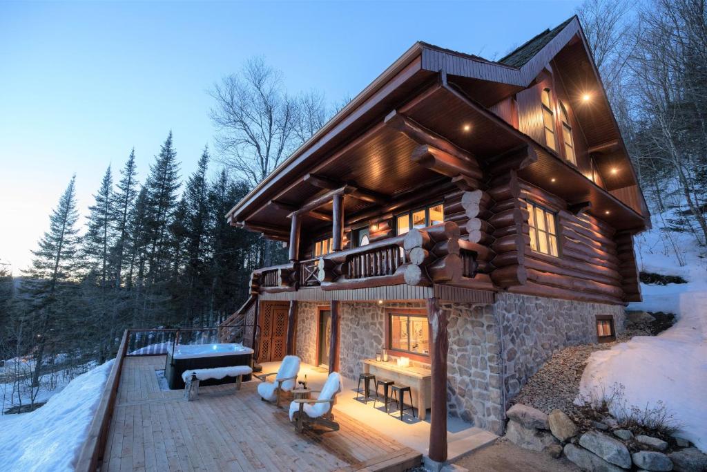 una cabaña de madera en el bosque en la nieve en Breathtaking log house with HotTub - Winter fun in Tremblant, en Saint-Faustin