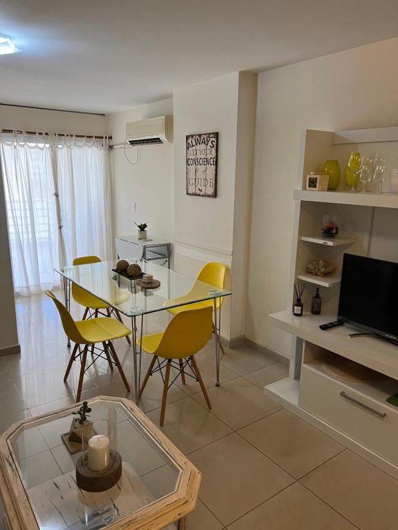 uma sala de estar com uma mesa de vidro e cadeiras amarelas em Departamento en pleno centro en complejo con Pileta y Gimnasio em Córdoba