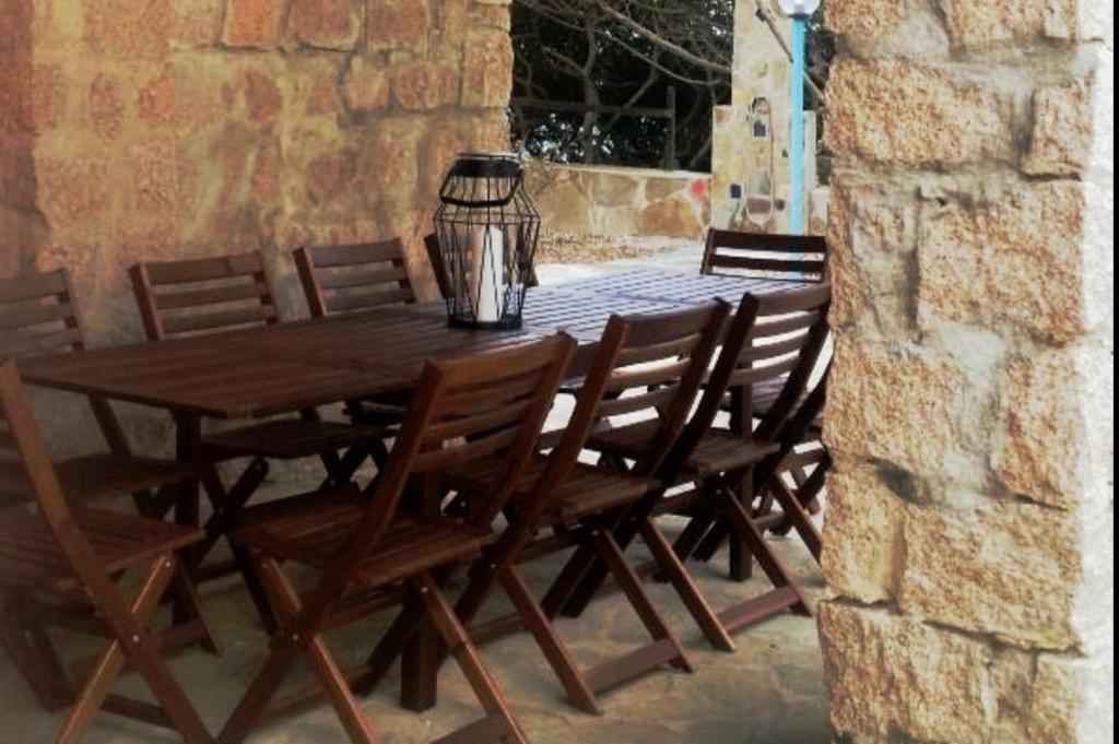 a wooden table with chairs and a vase on a patio at Villa Vera trifamigliare con ingresso diretto 20 mt al mare clima wi-fi bbq in Cala Liberotto