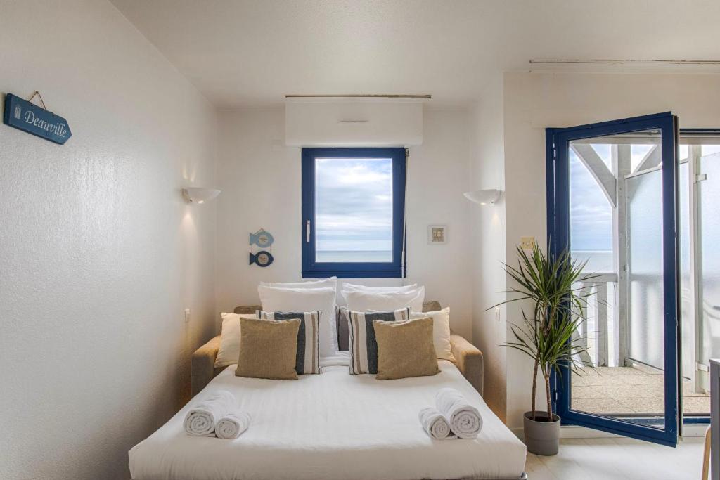 sypialnia z białym łóżkiem z poduszkami i oknem w obiekcie Les Tamaris - Studio with Sea View - Trouville-Sur-Mer w mieście Trouville-sur-Mer