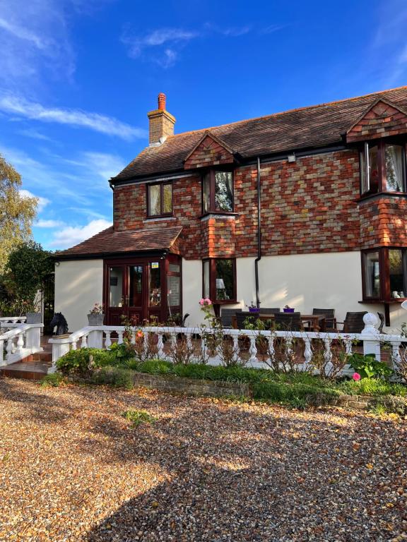 uma casa de tijolos com uma cerca branca em frente em Reynolds Farm Guesthouse em Canterbury