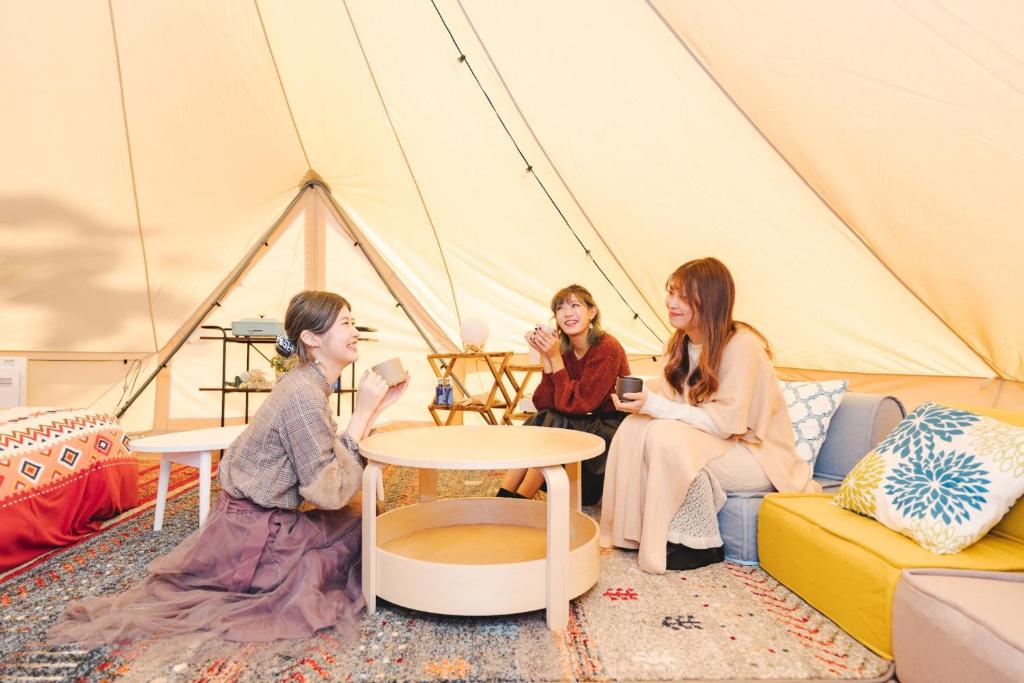 OKAYAMA GLAMPING SORANIA - Vacation STAY 73233v في كوراشيكي: مجموعة نساء جالسات في خيمة