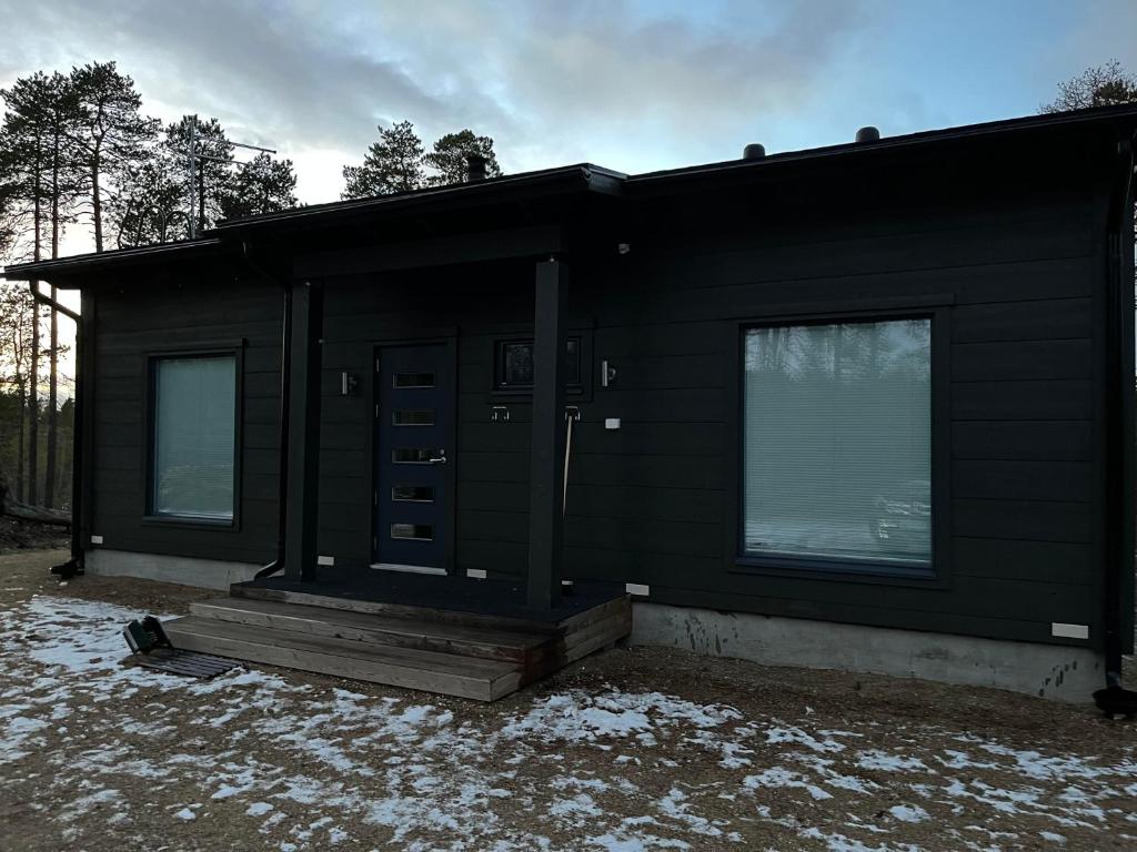 Una casa negra con una puerta y ventanas. en Villa Paadar, en Inari