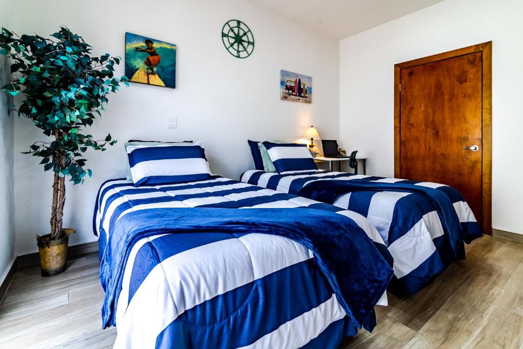 twee bedden in een kamer met blauwe en witte lakens bij Milan San Marino in Tijuana
