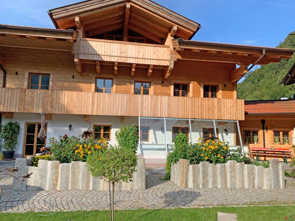 a large wooden house with flowers in front of it at Ferienwohnungen Kieferbachtal in Kiefersfelden