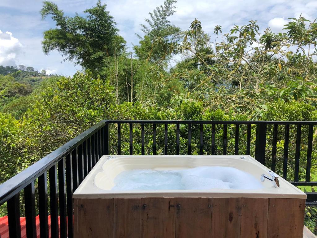 a hot tub on a balcony with a black fence at Cabaña tipo glamping en finca cafetera con zonas verdes, avistamiento de aves, paisaje cafetero in San Francisco