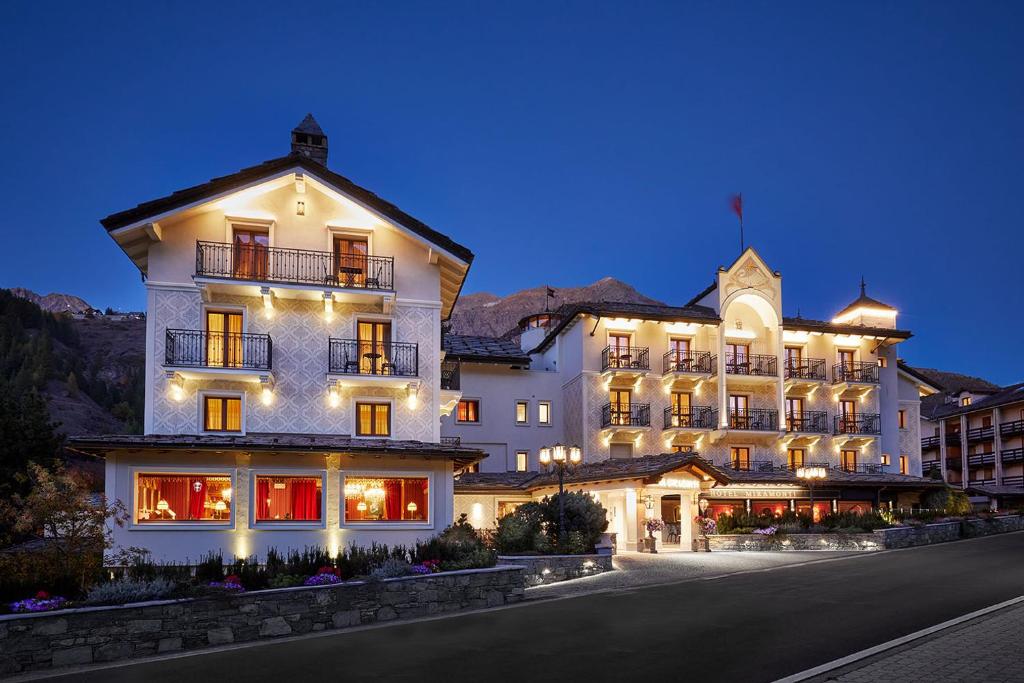 een groot wit gebouw met 's nachts verlichting bij Hotel Miramonti in Cogne