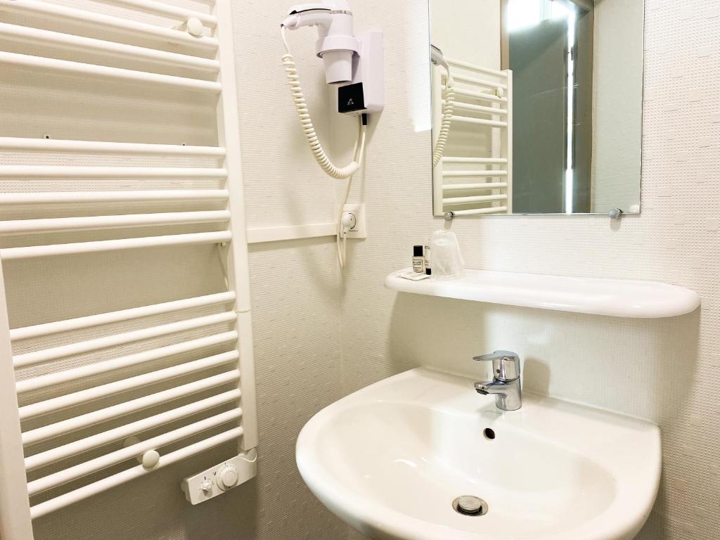 a white bathroom with a sink and a mirror at Colette Hôtel in Niort