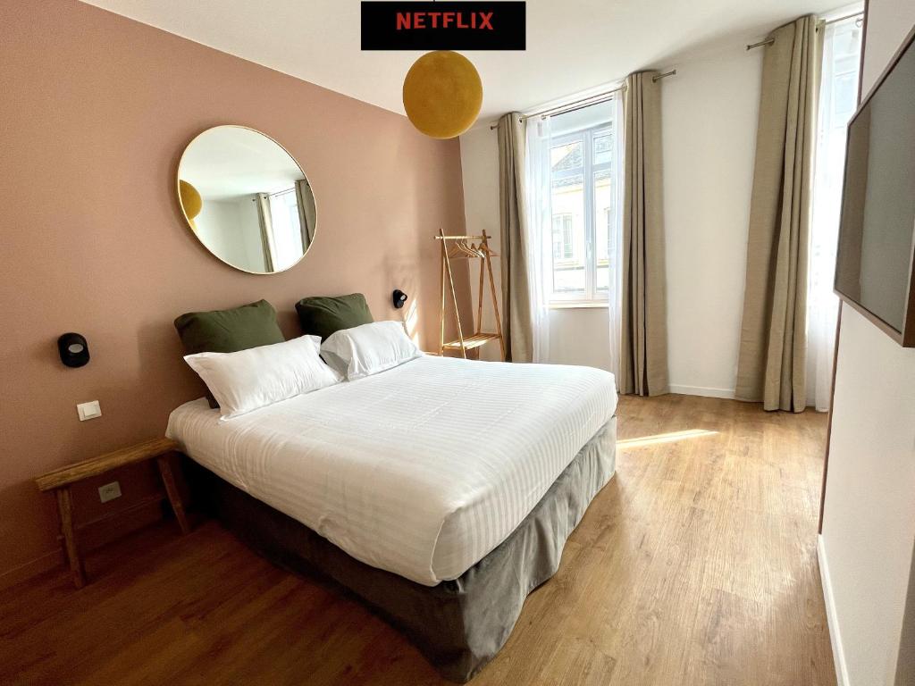 Demeure Rossini Cholet Centre في شوليه: غرفة نوم بسرير كبير ومرآة