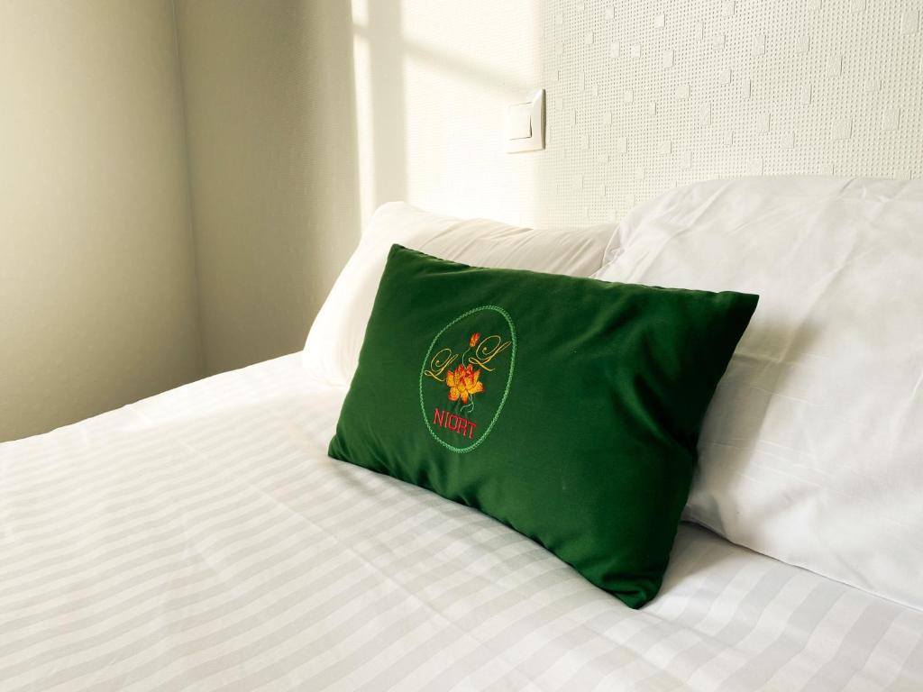 a green pillow sitting on top of a bed at Colette Hôtel in Niort