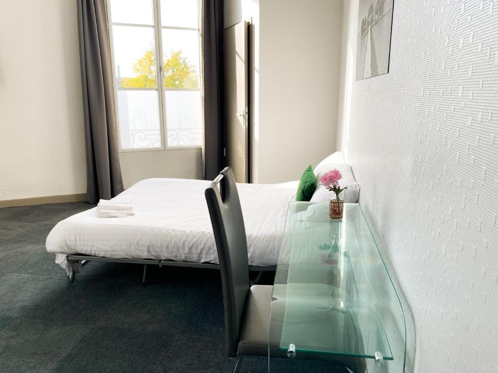 a room with a bed and a glass table at Colette Hôtel in Niort