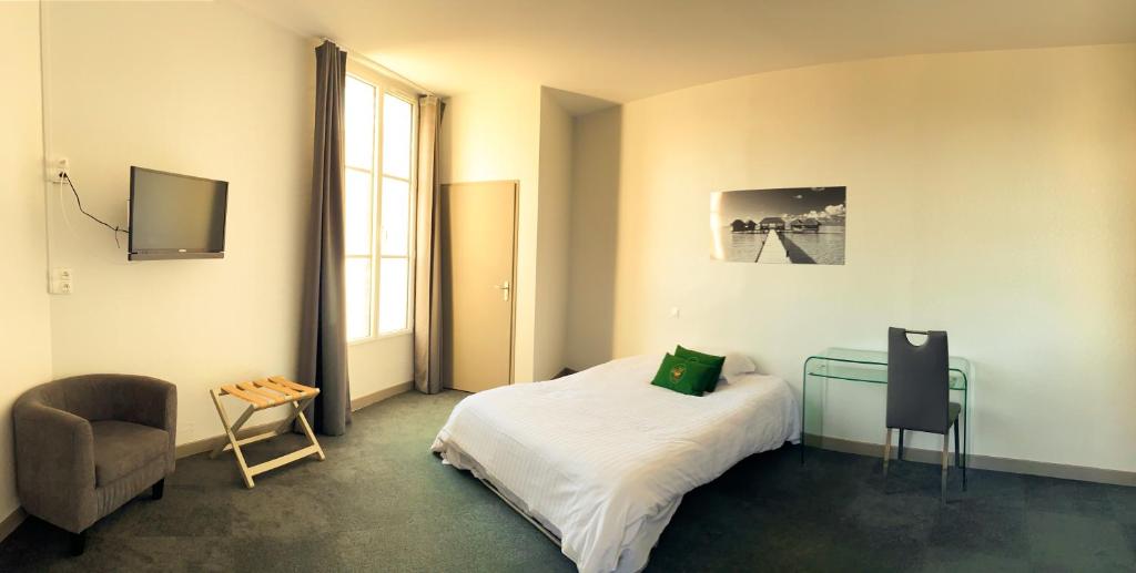 a bedroom with a bed and a desk and a chair at Colette Hôtel in Niort