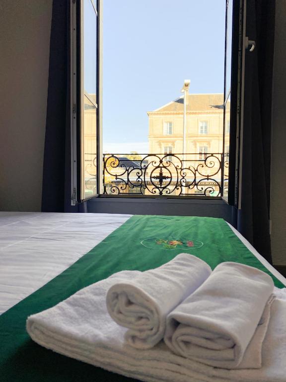 a room with a bed with towels and a window at Colette Hôtel in Niort