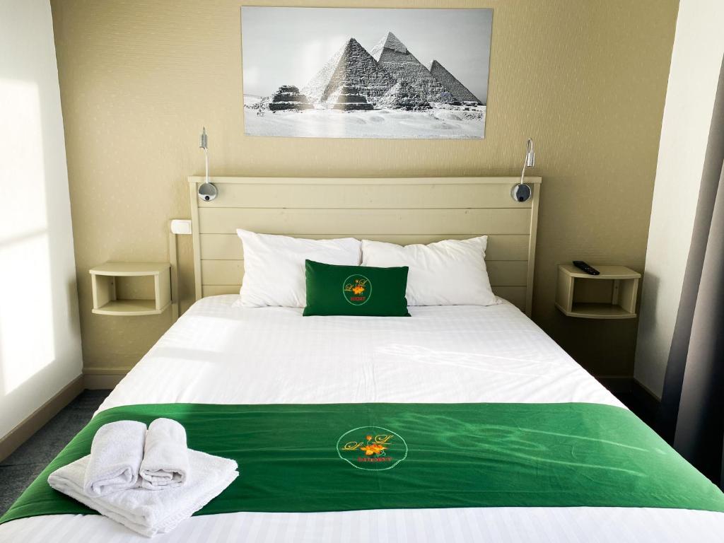 a bedroom with a bed with a green blanket and the pyramids at Colette Hôtel in Niort