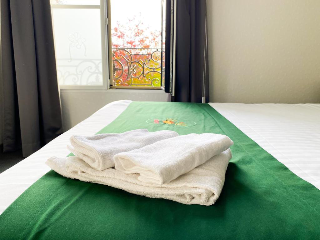 a pile of towels sitting on a bed with a window at Colette Hôtel in Niort