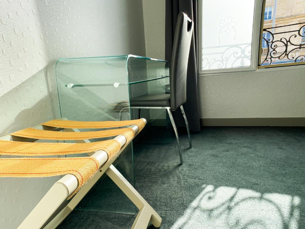 a glass bench in a room with a chair at Colette Hôtel in Niort