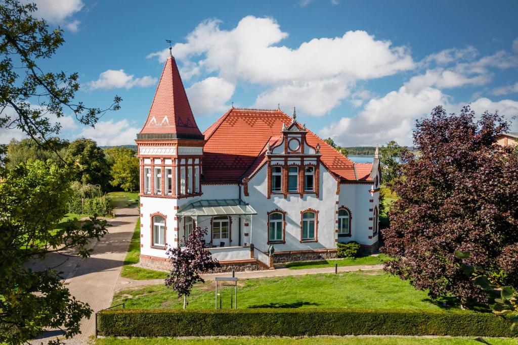 ein altes Haus mit einem Turm auf einem Rasen in der Unterkunft Hotel Villa am Stadthafen in Neustrelitz
