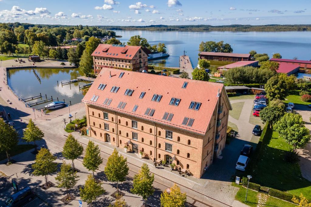 eine Luftansicht eines Gebäudes mit einem See im Hintergrund in der Unterkunft Hotel Alter Kornspeicher in Neustrelitz