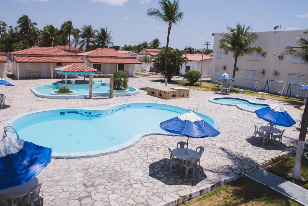 uma piscina com mesas e guarda-sóis num resort em CALDAS PALACE HOTEL JORRO em Tucano