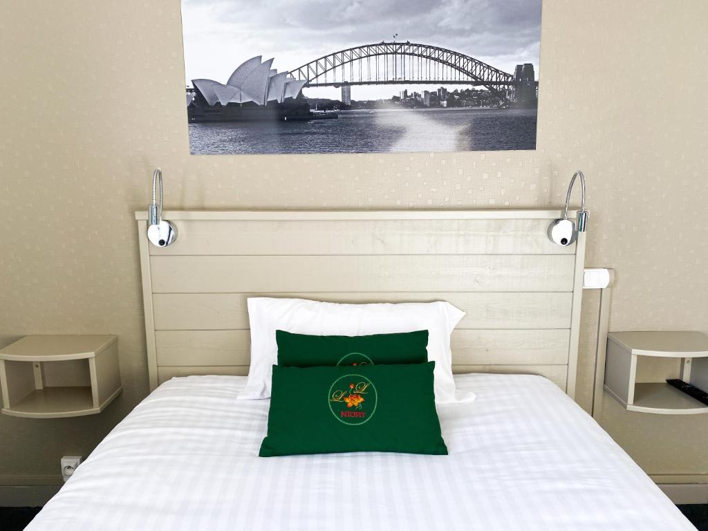 a bedroom with a bed with a green pillow on it at Colette Hôtel in Niort