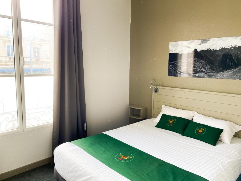 a bedroom with a bed with two green pillows at Colette Hôtel in Niort