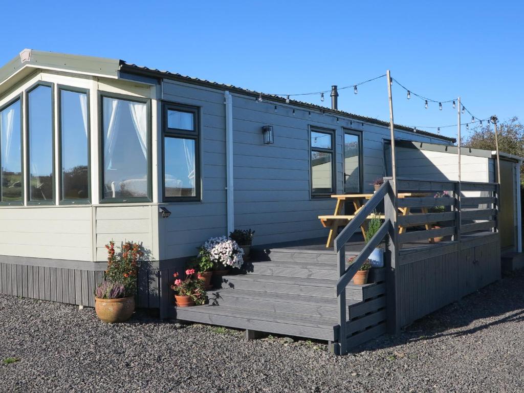a tiny house with a staircase and a deck at Plas Tirion Caravan in Holyhead