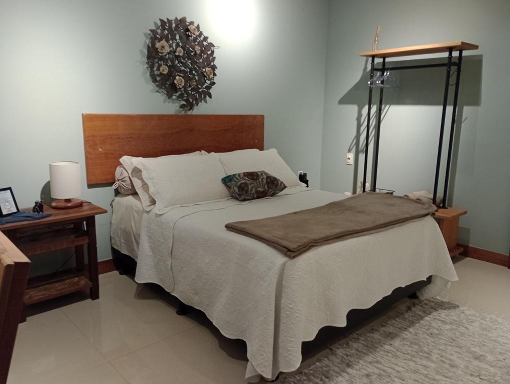 a bedroom with a bed and a table with a lamp at Casa da Lu Itacoatiara -Suite Alto Mourão in Niterói