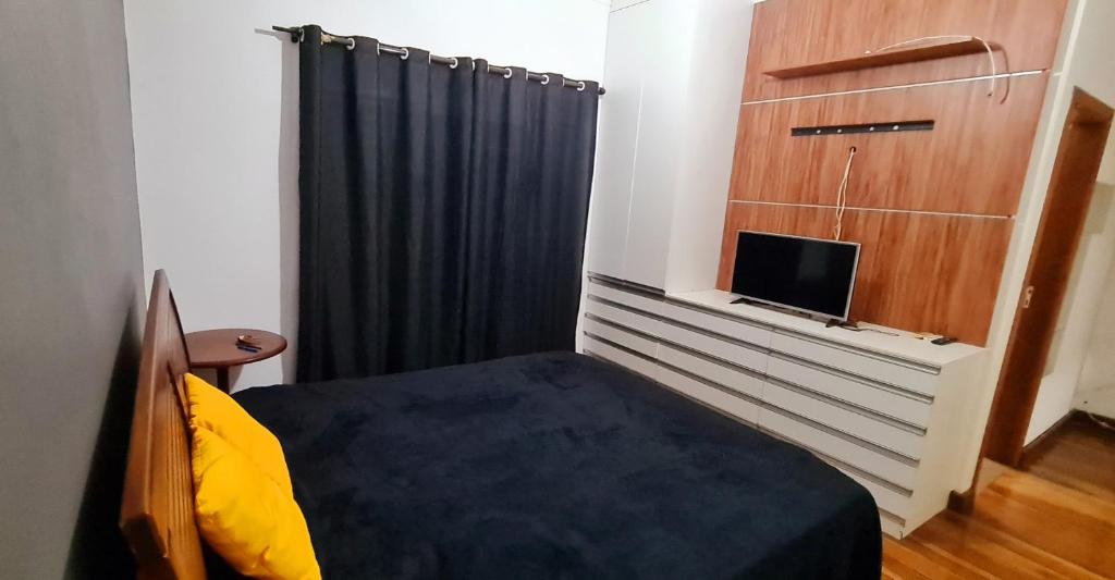a small bedroom with a bed and a television at Casa com banheira para até 12 pessoas prox USP-HC fácil acesso para Arena EUROBIKE com Wi-Fi in Ribeirão Preto