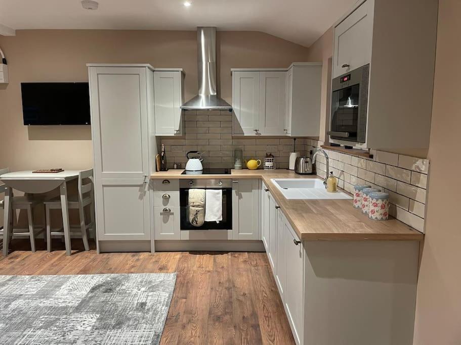 a kitchen with white cabinets and a sink at Tulip Cottage in Wisborough Green