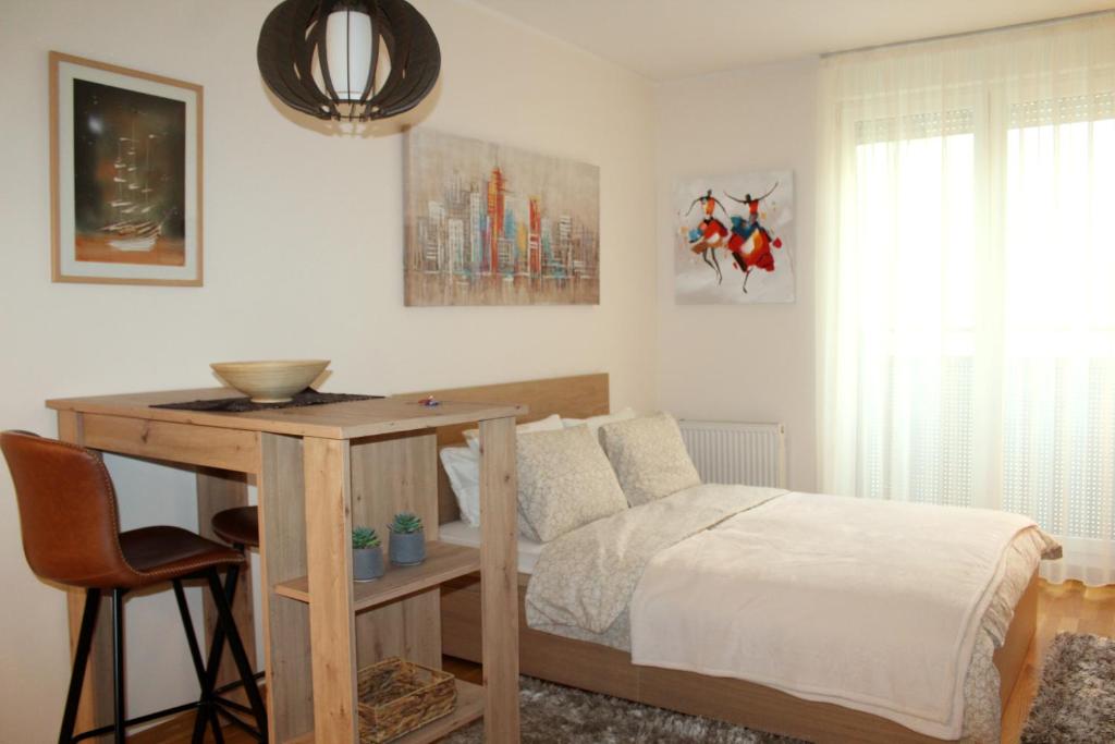 a bedroom with a bed and a table with a desk at Downtown Apartment in Novi Sad