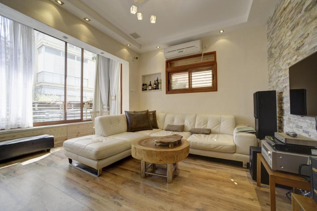 een woonkamer met een bank en een tafel bij Sunset TLV Apartment - Dizengoff 142 in Tel Aviv