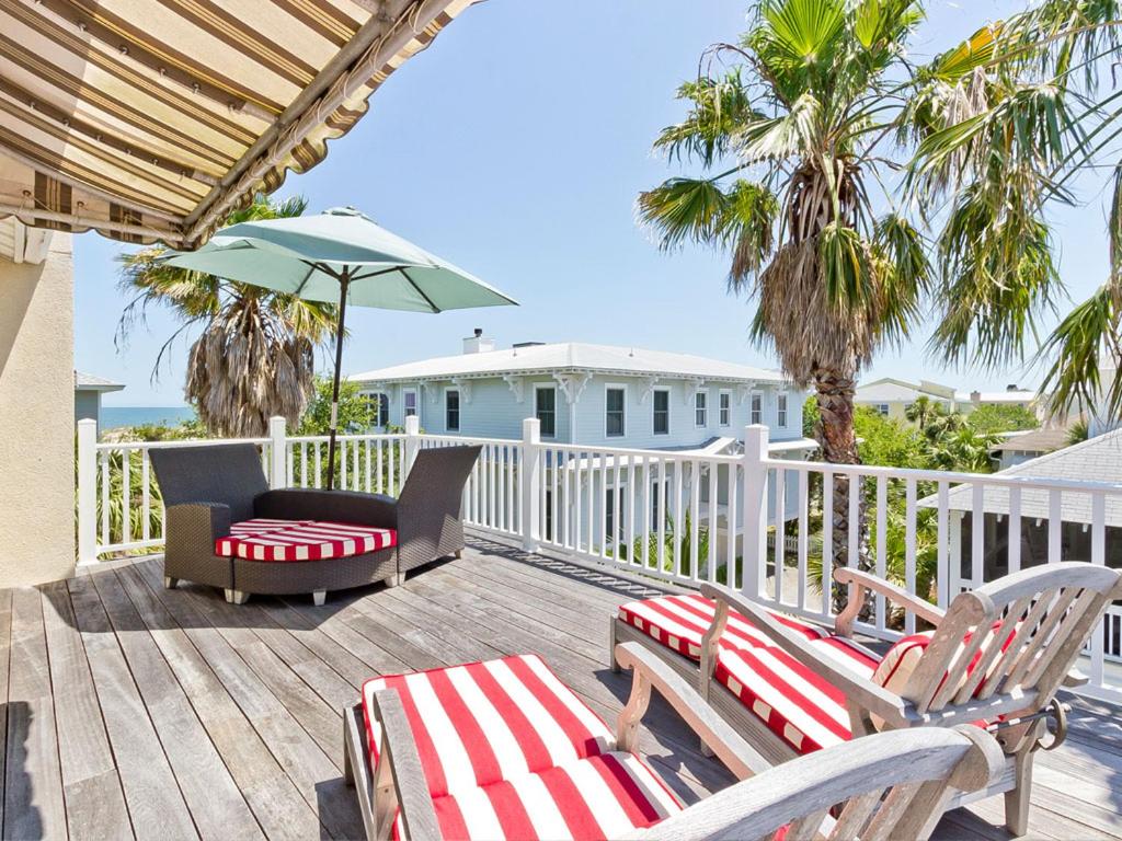 a deck with two chairs and a table and an umbrella at Driftaway in Tybee Island