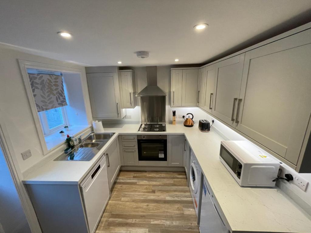 a kitchen with white cabinets and a sink at Ebor Mill's Cottage in Haworth