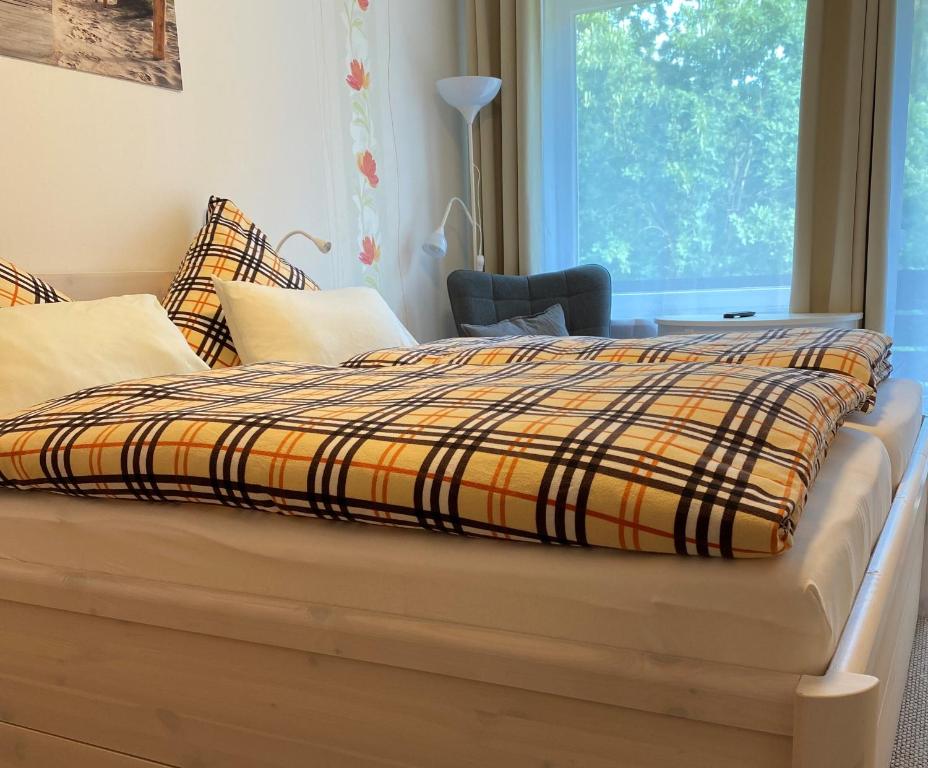 a bed with a plaid blanket on top of it at Gästehaus Falkenhof in Westensee