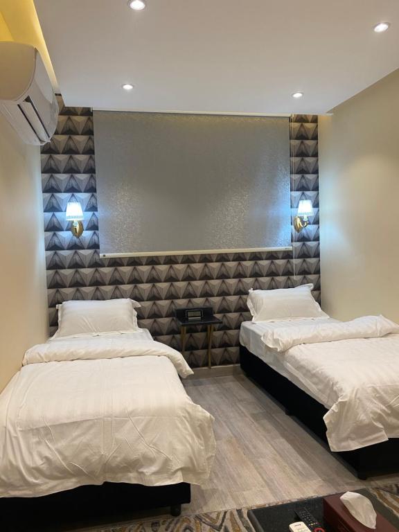 una stanza con due letti e un muro di فندق المنصور a Aḑ Ḑabbīyāt al Janūbīyāt