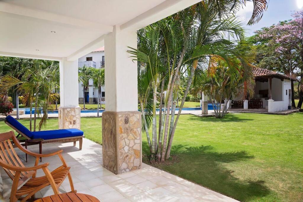 a porch with a blue chair and a yard at Golf Condo A1 F1: Nice view and access to the largest pool in Hacienda Iguana! in Rivas