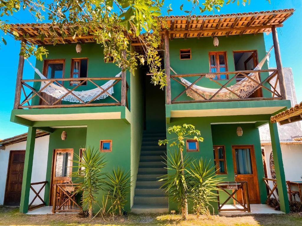 a green house with a staircase in front of it at Pousada Tamikuã in Caraíva