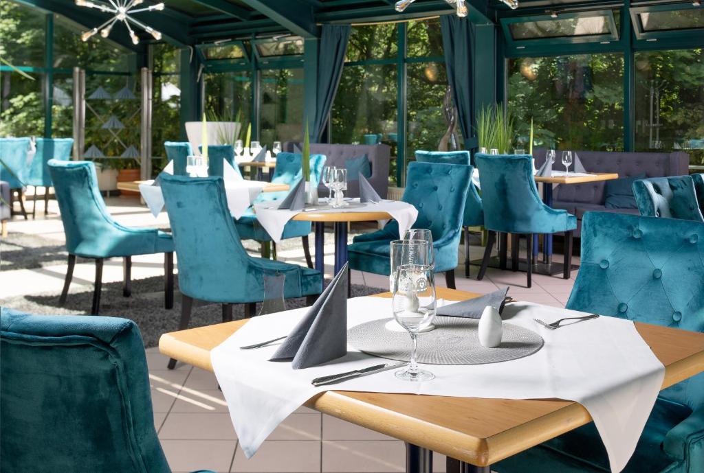 a restaurant with blue chairs and tables with wine glasses at Parkhotel Waldschlösschen in Annaberg-Buchholz