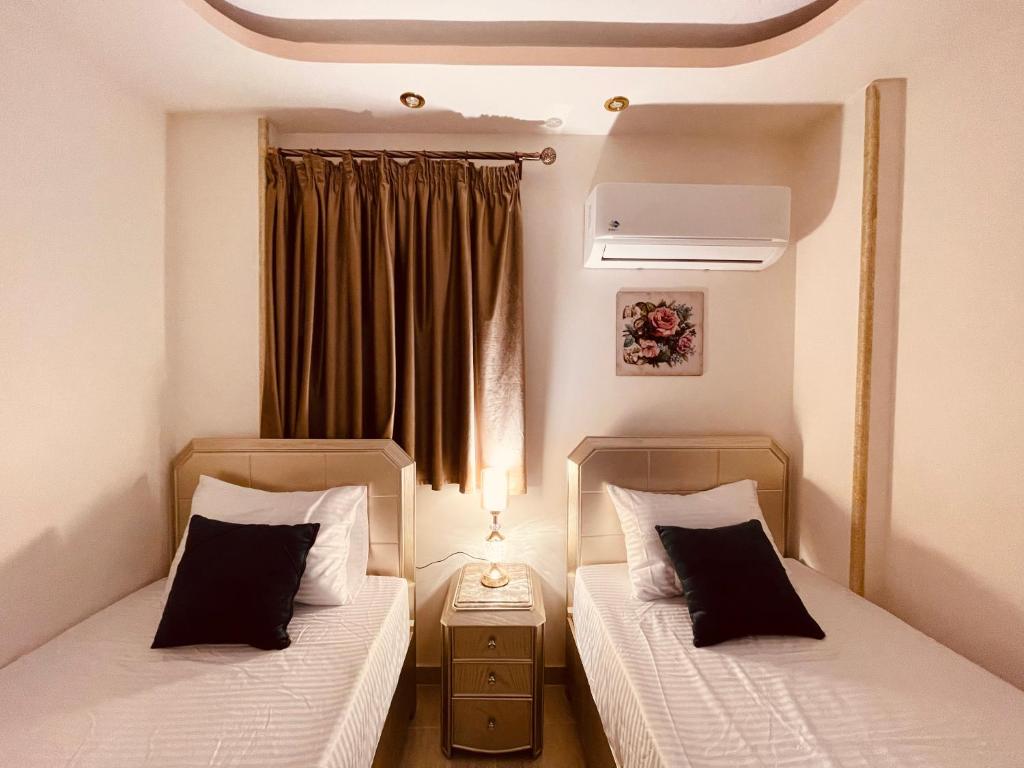 2 camas en una habitación pequeña con ventana en El mansour hotel apartmen 81, en El Mansurá