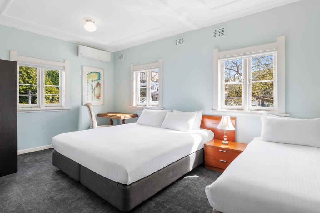 two beds in a room with two windows at Hotel Blue & Cottages Katoomba in Katoomba