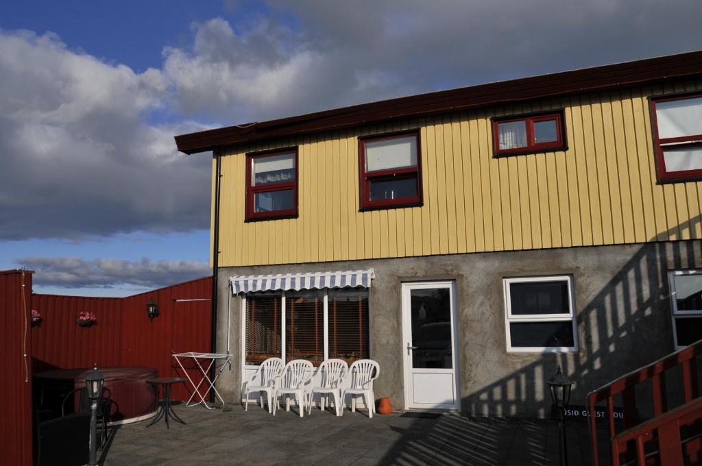 un gruppo di sedie bianche sedute su un patio accanto a un edificio di Húsid Guesthouse a Reykholt