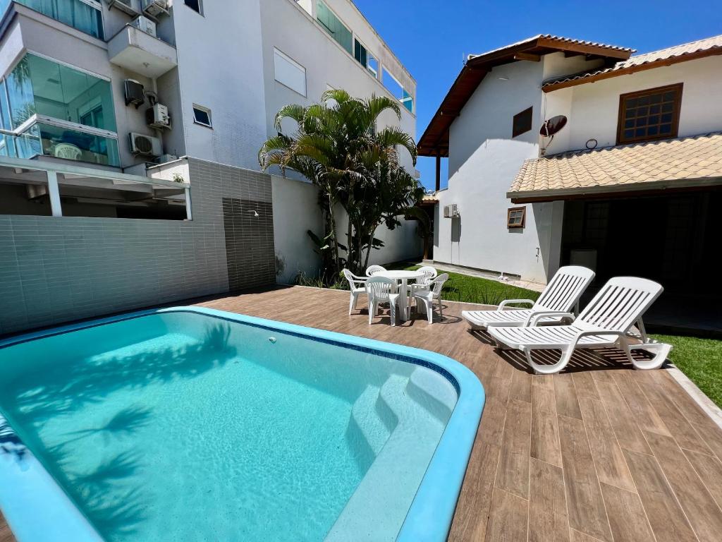a backyard with a swimming pool and two chairs and a table at Casa a 50 M do Mar Para Recarregar as Energias in Bombinhas