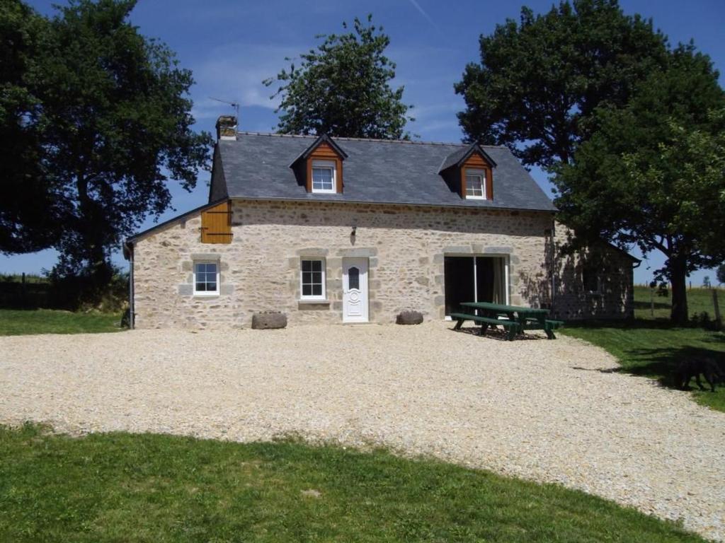 een stenen huis met een picknickbank ervoor bij Gîte Saint-Léonard-des-Bois, 5 pièces, 7 personnes - FR-1-410-179 in Saint-Léonard-des-Bois