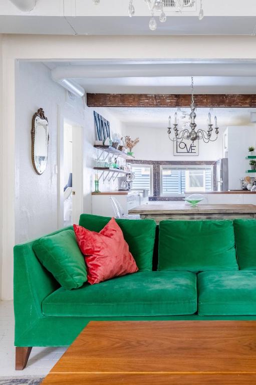 Hotel Boutique Apartment in 1905 Victorian Home - Plaza - Westport, a green couch in a living room with a kitchen at Boutique Apartment in 1905 Victorian Home - Plaza - Westport in Kansas City