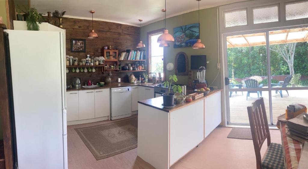 a large kitchen with white cabinets and a table at Okato Homestay in Okato