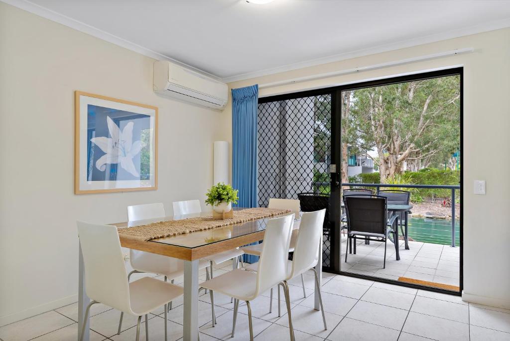 a dining room with a table and white chairs at North Facing, 2 bedroom Townhouse in Tropical Resort in Noosaville